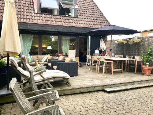 una terraza de madera con sillas, mesas y sombrilla en Rivera Hill, en Båstad