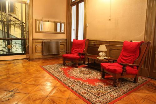 a living room with two red chairs and a table at Hotel Reina in Buenos Aires