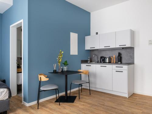 a kitchen with a table and chairs and a blue wall at Limehome Augsburg Annastraße in Augsburg