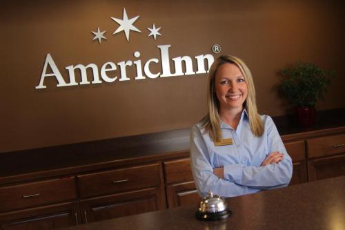 a woman standing at a counter with her arms crossed at AmericInn by Wyndham Plymouth in Plymouth