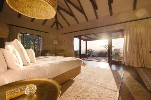 a bedroom with a large bed and a large window at Tomjachu Bush Retreat in Nelspruit