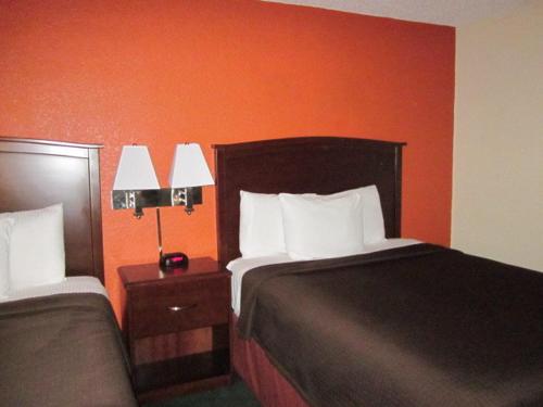 a hotel room with two beds and an orange wall at AmericInn by Wyndham Plymouth in Plymouth