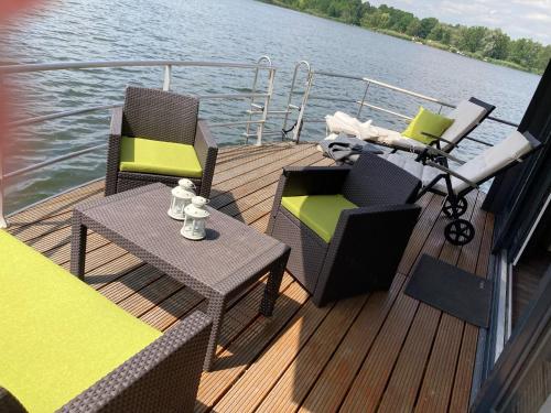 una terraza con 2 sillas y una mesa en un barco en Schwimmende Ferienwohnung, Hausboot Urlaub als Festlieger am Steg, en Zehdenick