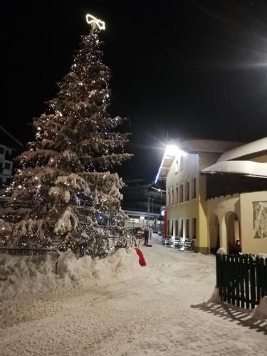 a christmas tree covered in snow next to a building at Cesa de Conesel in Colle Santa Lucia