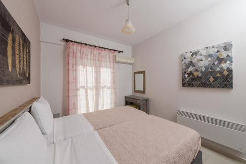a white bedroom with a bed and a window at Punda 4 Seasons in Diakopto