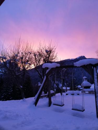 a swing set in the snow with a sunset in the background at Cesa de Conesel in Colle Santa Lucia