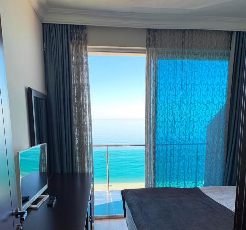 a bedroom with a large window with a view of the ocean at Hotel Neptun Kvariati in Kvariati