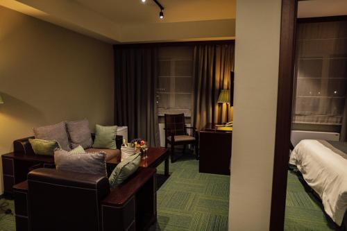 a hotel room with a couch and a bedroom at Hotel Dastan Aktobe in Aktobe