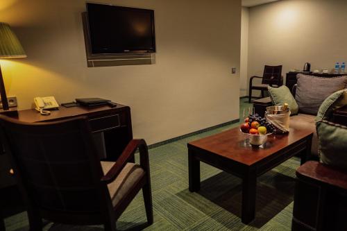 a living room with a couch and a table with a bowl of fruit at Hotel Dastan Aktobe in Aktobe