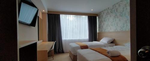 a hotel room with two beds and a window at Hotel Lereng Bromo in Pasuruan