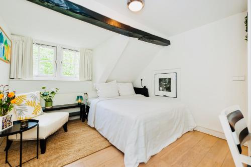 a white bedroom with a bed and a couch at B&B De Smederij in Amerongen