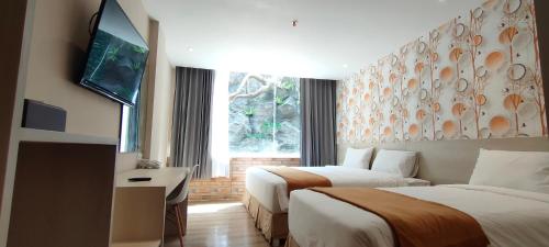 a hotel room with two beds and a television at Hotel Lereng Bromo in Pasuruan