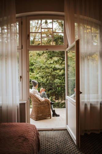 two people sitting in a chair on a porch at Hotel Dębowy Biowellness & SPA Góry Sowie in Bielawa