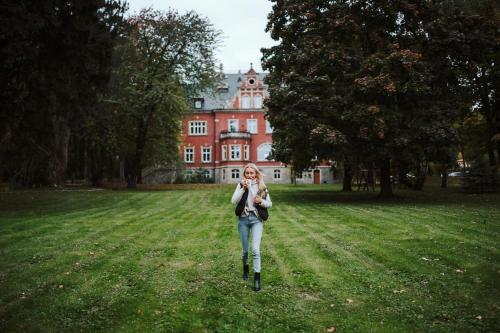 a woman walking in the grass in front of a house at Hotel Dębowy Biowellness & SPA Góry Sowie in Bielawa