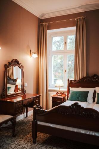 a bedroom with a bed and a desk and a window at Hotel Dębowy Biowellness & SPA Góry Sowie in Bielawa