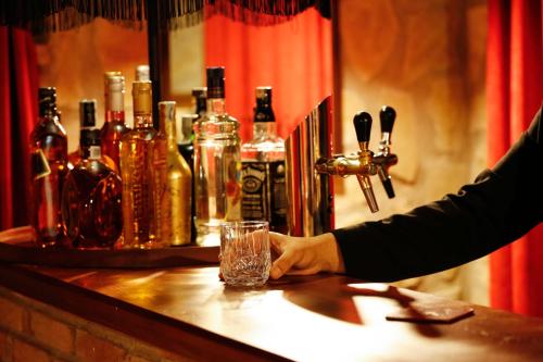 a person holding a glass at a bar with bottles at Hotel Memoire Kutaisi in Kutaisi