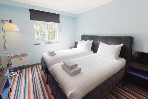 two beds in a hotel room with towels on them at Village Hotel Nottingham in Nottingham