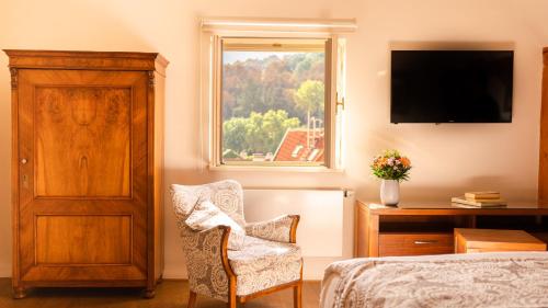 a bedroom with a bed and a chair and a window at Hotel Golden Key Prague Castle in Prague