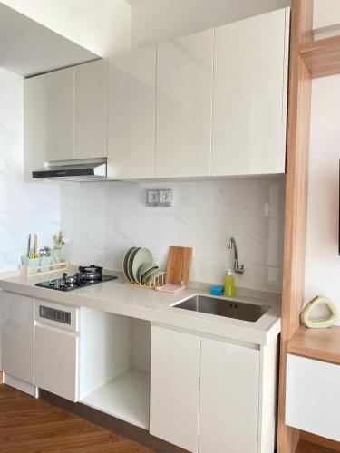 a white kitchen with white cabinets and a sink at lalerooms Warm and cozy Studio at Skyhouse BSD find us on ig lalerooms in Tangerang