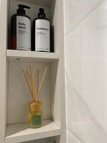 a shelf with two bottles of soap and some sticks at lalerooms Warm and cozy Studio at Skyhouse BSD find us on ig lalerooms in Tangerang