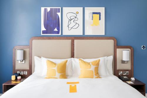 voco Grand Central Glasgow, an IHG Hotel في غلاسكو: غرفة نوم بسرير ابيض كبير بجدران زرقاء