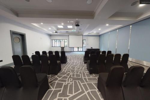 a conference room with chairs and a screen and a podium at Village Hotel Leeds North in Leeds