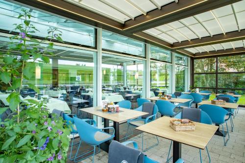 a restaurant with tables and chairs and windows at Hotel Regina Maris in Norddeich