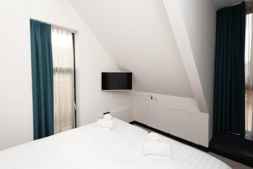 a bedroom with two beds and a tv on the wall at Welcome in - Bomont appartementen 4 persoons - Jan van Renesseweg 1 Renesse in Renesse