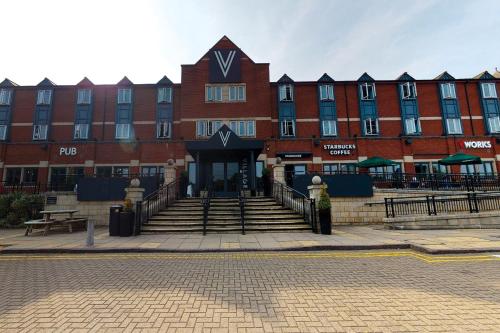 a large red brick building with stairs in front of it at Village Hotel Coventry in Coventry