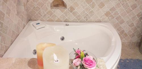 Una bañera blanca con una vela y flores. en Casale vita nova, en Manciano