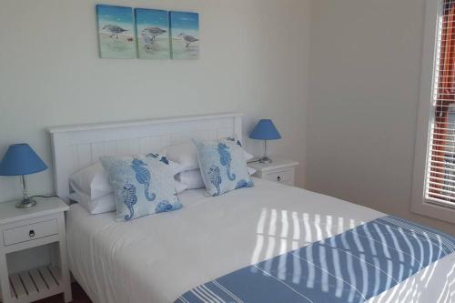 Schlafzimmer mit einem Bett mit blauen und weißen Kissen in der Unterkunft 18 Steps - Seaside Cottage with breathtaking views in Kapstadt