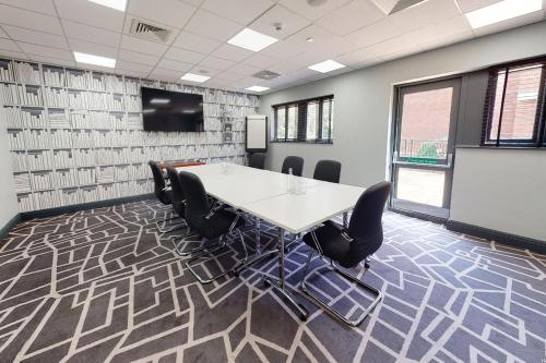 a conference room with a table and chairs and a screen at Village Hotel Coventry in Coventry