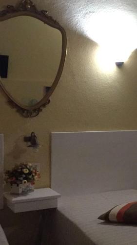 a bathroom with a mirror and a bed and a sink at Affittacamere Caliani in Buonconvento