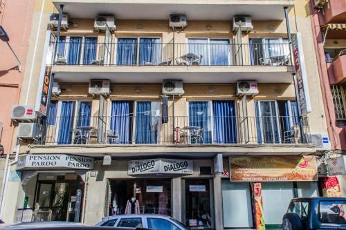 un edificio con balconi e auto parcheggiate di fronte ad esso di Pensión Pardo a Benidorm