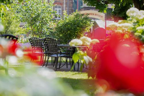 a table and chairs in a garden with flowers at Hotel Lindenhof Bad Schandau in Bad Schandau