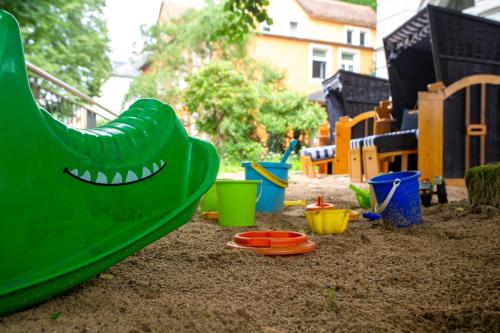 einen Spielplatz mit einer grünen Rutsche im Sand in der Unterkunft Hotel Lindenhof Bad Schandau in Bad Schandau