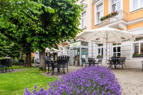 Hotel Lindenhof Bad Schandau في باد شانداو: مجموعة من الطاولات والكراسي والزهور الأرجوانية