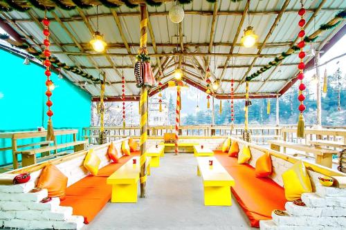 une rangée de bancs jaunes et oranges dans un pavillon dans l'établissement The Culture Nation Hostel Manali, à Manali