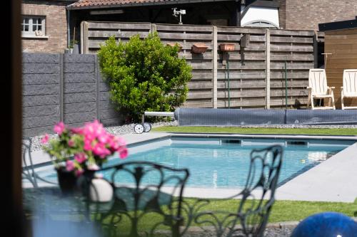 a pool with two chairs and a table with pink flowers at Bed & Breakfast 't Vèèrke in Dilsen-Stokkem