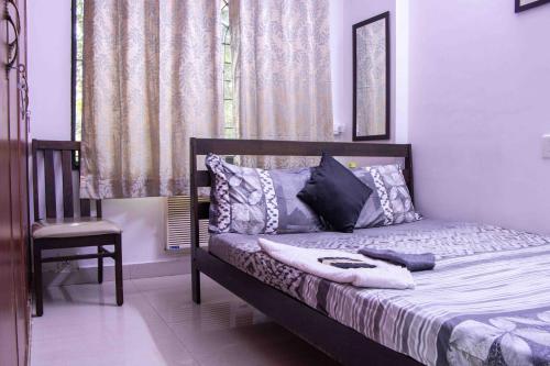 a bedroom with a bed with a chair and a window at Greams Road Near - Apollo - Fusion Serviced Apartments in Chennai