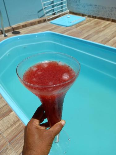 a person holding a drink in a martini glass at Pousadinha da Lulu - Pontal Mangue Seco in Indiaroba
