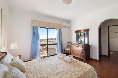 a bedroom with a bed and a dresser and a window at Casa da Alfarrobeira in Loulé