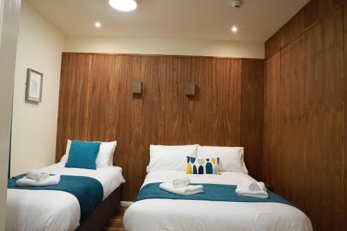 two beds in a room with wood paneling at Hazeldean in Manchester