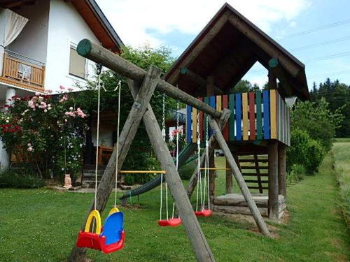 a playground in front of a house with swings at Ferienwohnung Silvia in Sankt Kanzian