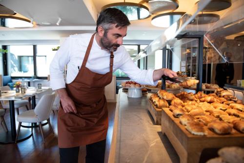 a man standing in a kitchen preparing food at Athens Capital Center Hotel - MGallery Collection in Athens