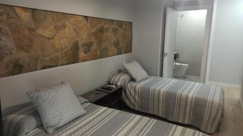 a bedroom with two beds and a rock wall at Alcazaba - Free Parking in Mérida