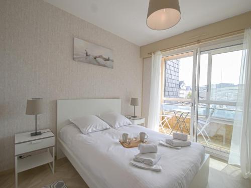 a bedroom with a large white bed with towels on it at Le Gréement - Appt vue sur le port in Courseulles-sur-Mer