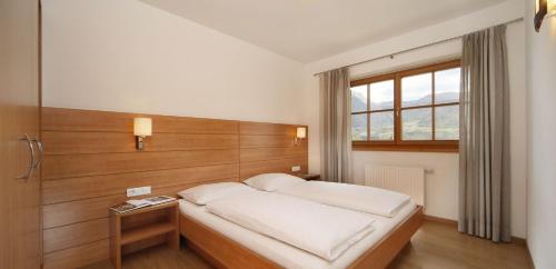 Schlafzimmer mit einem Bett mit einem Kopfteil aus Holz in der Unterkunft Zieglerhof Appartement 3 in Marling