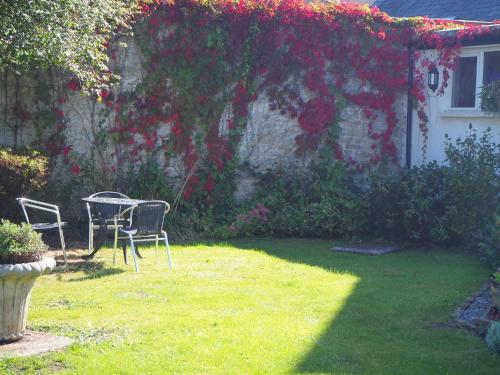 a garden with a table and chairs in the grass at Meare Manor in Glastonbury