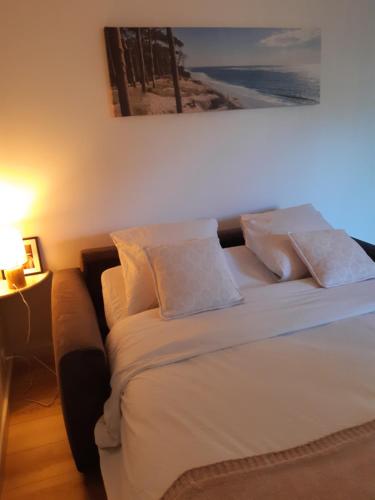 une chambre avec un lit avec des draps blancs et des oreillers dans l'établissement Un jardin en ville, à Talence